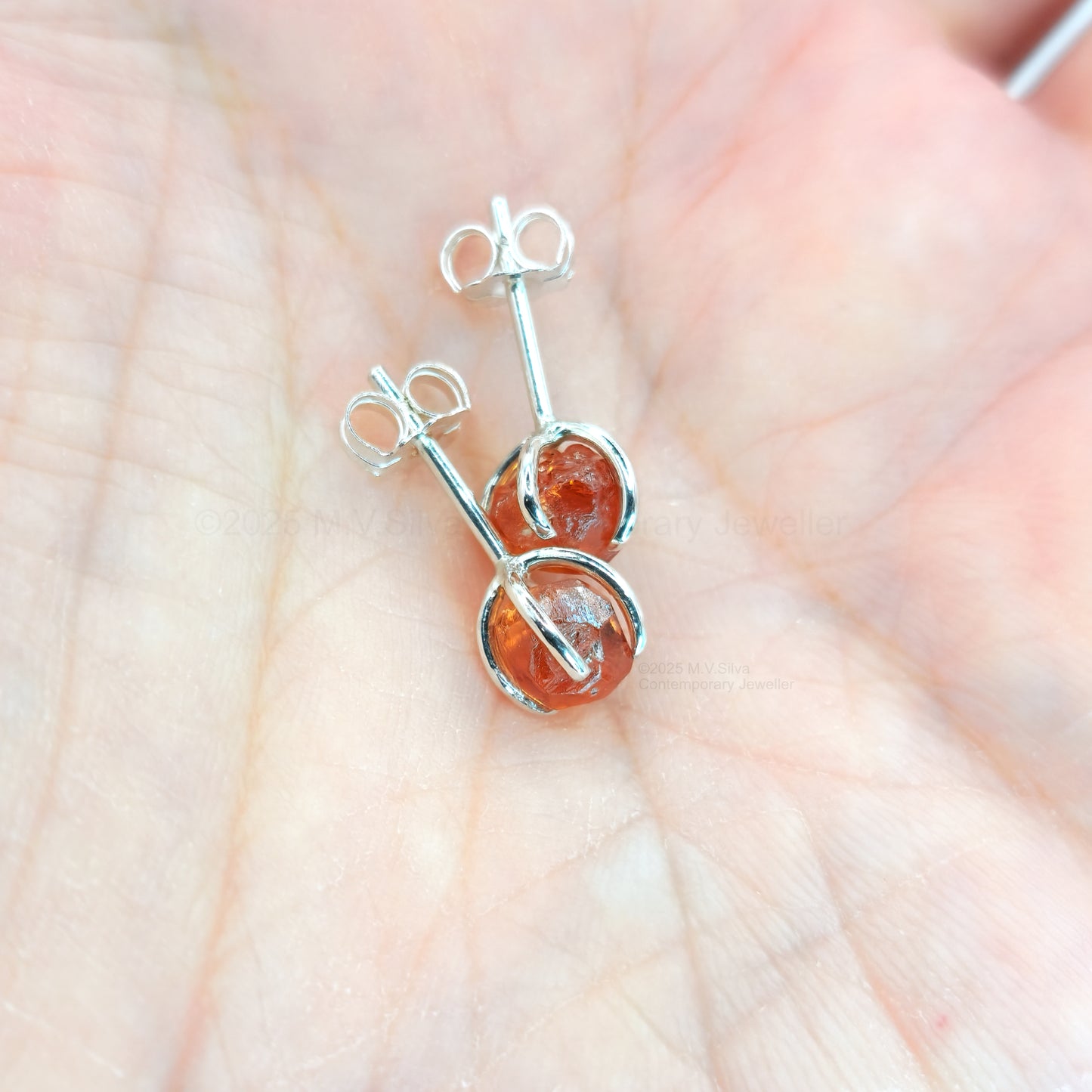 raw spessartine garnet silver studs in palm