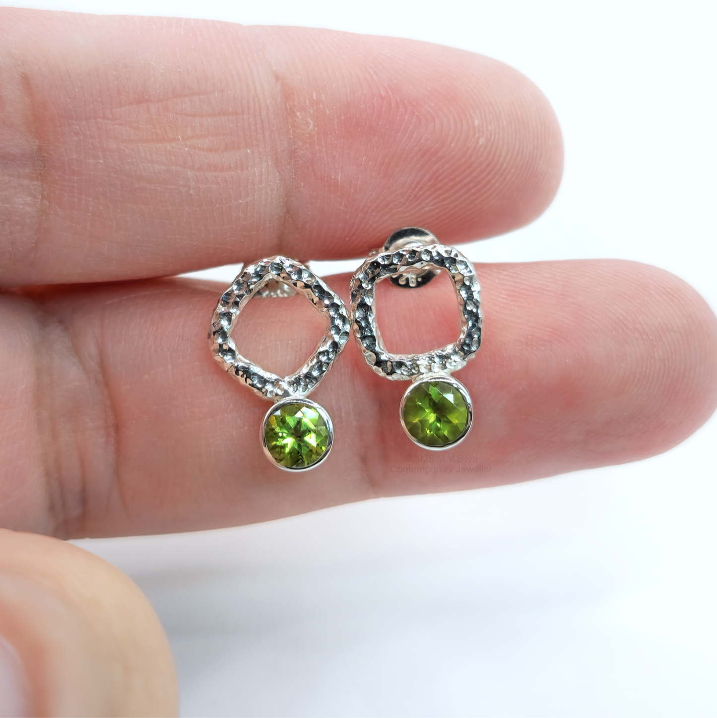 asymmetrical peridot earrings in hand