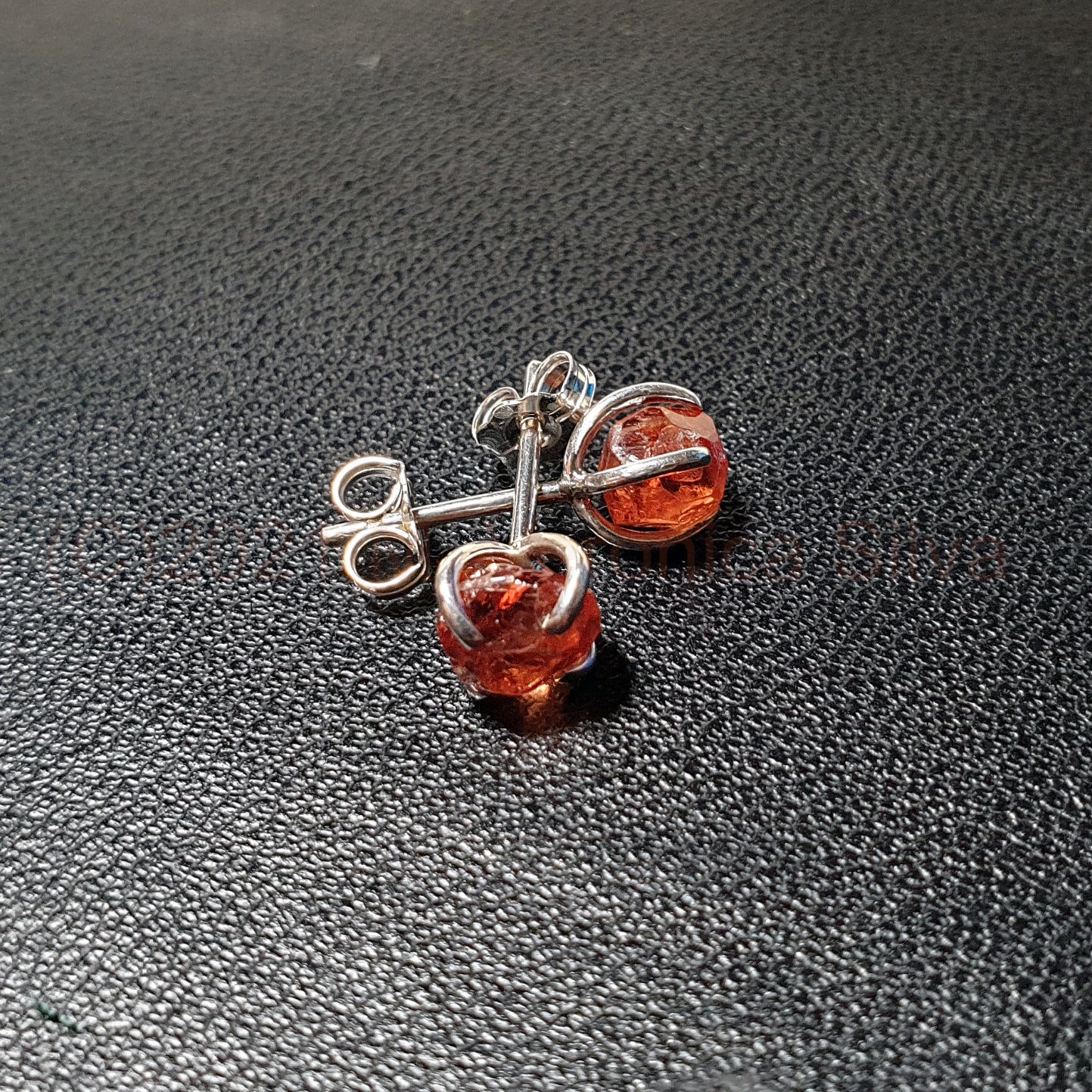 raw spessartine garnet silver studs on black bg