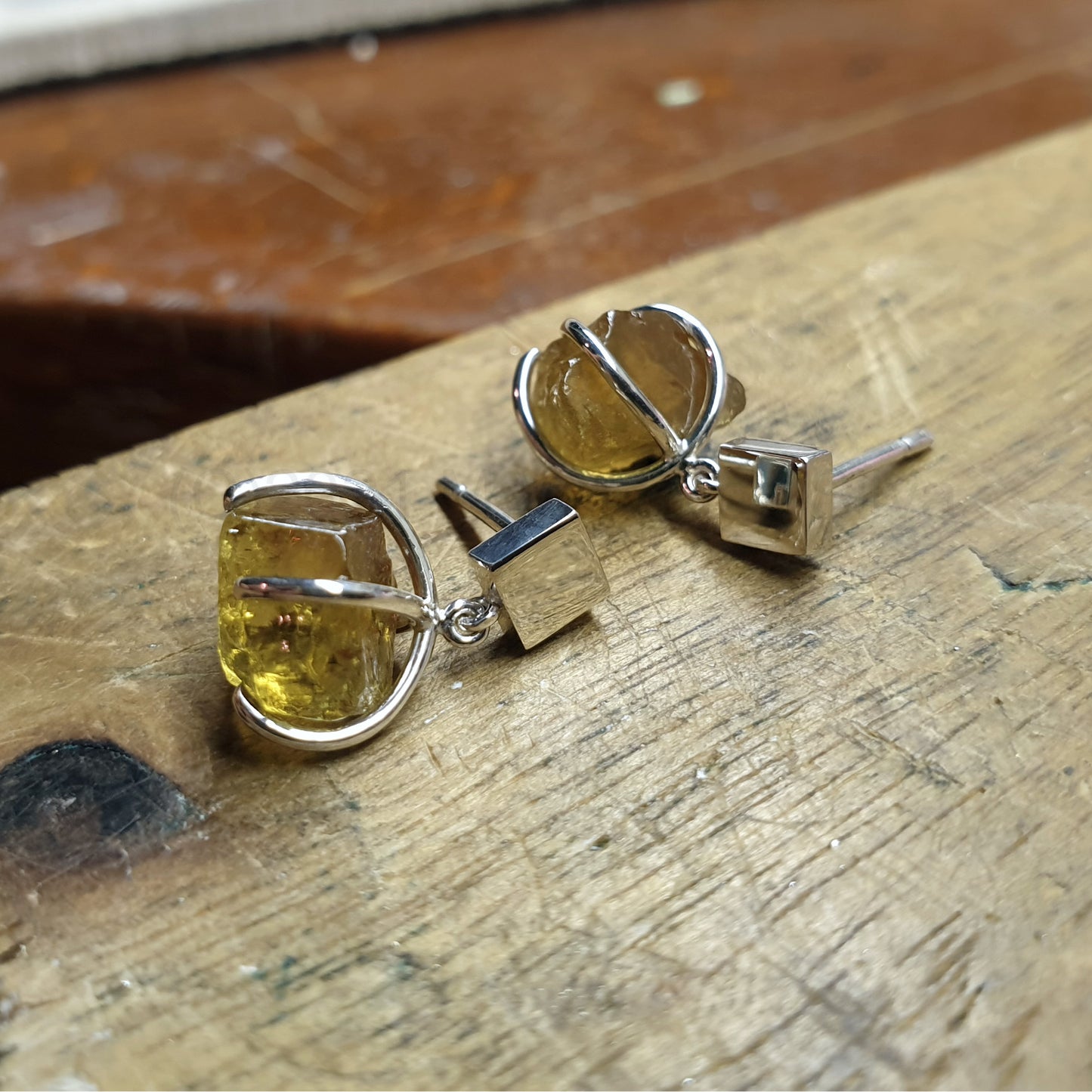 golden yellow apatite, square silver studs on wooden background